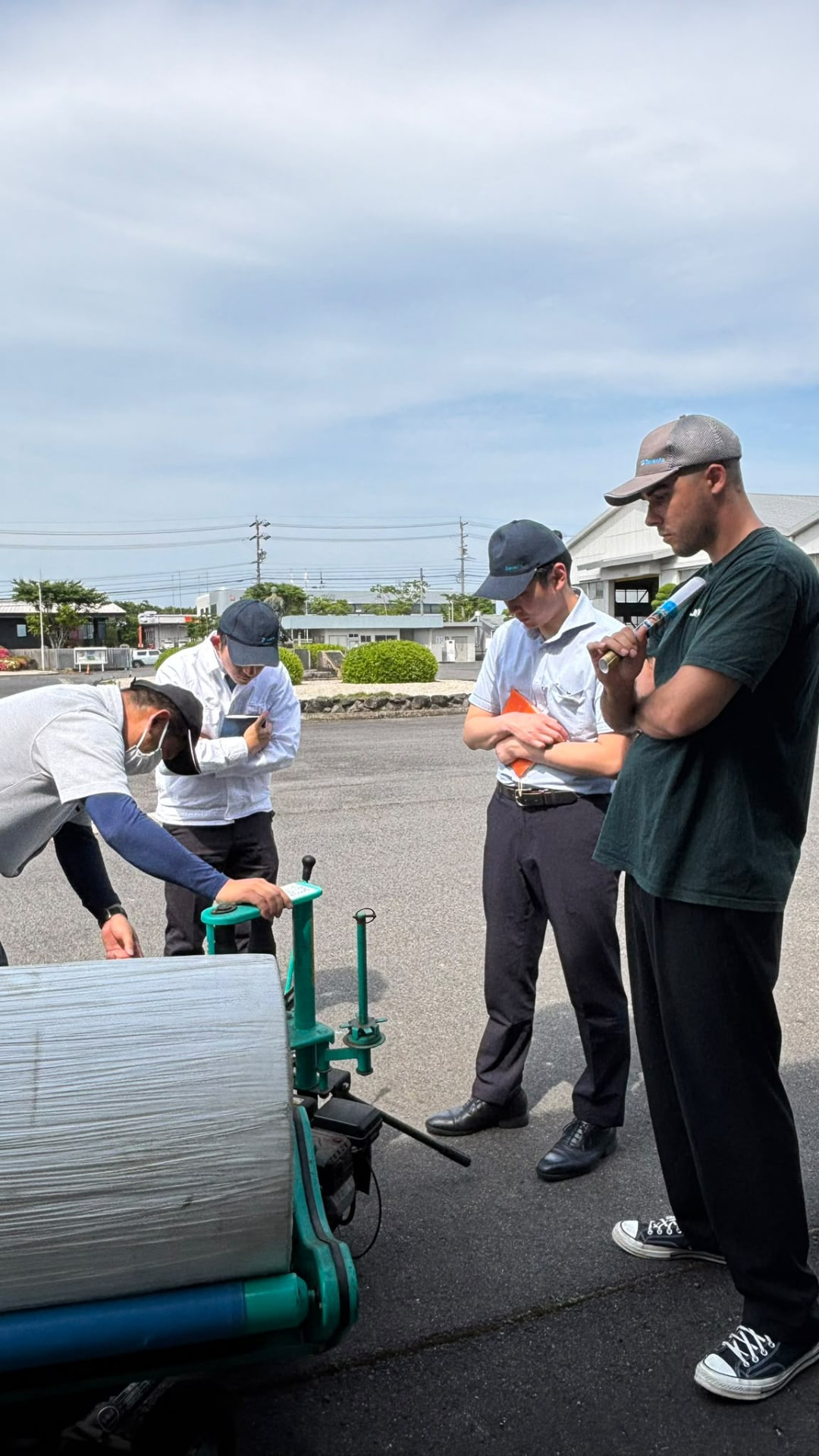 The teams discussing Takakita bale-wrapping equipment during the factory visit.
